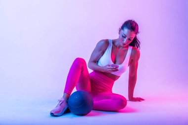 Spor kıyafetleri giymiş atletik bir kadın stüdyoda spor yapıyor.
