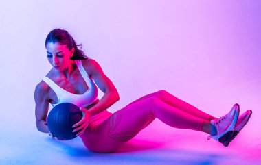 Spor kıyafetleri giymiş atletik bir kadın stüdyoda spor yapıyor.