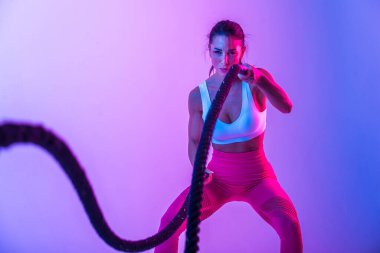 Spor kıyafetleri giymiş atletik bir kadın stüdyoda spor yapıyor.