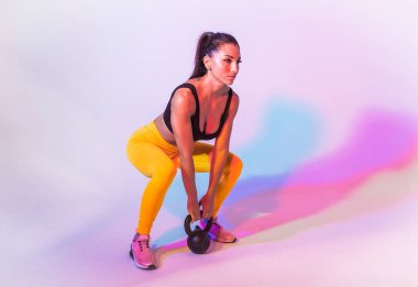 Spor kıyafetleri giymiş atletik bir kadın stüdyoda spor yapıyor.