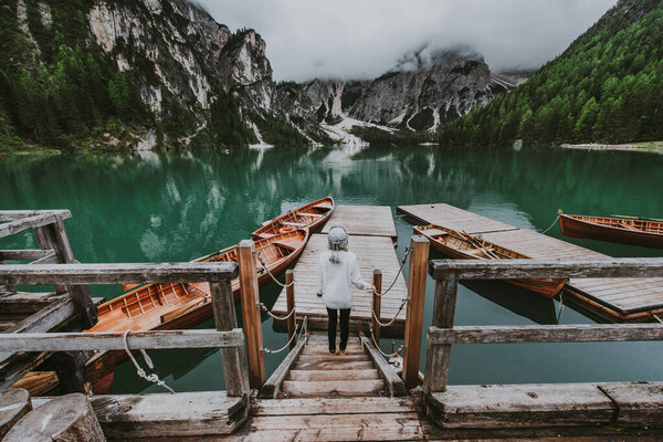 Beautiful woman visiting an alpine lake at Braies, Italy - Tourist with hiking outfit having fun on vacation during autumn foliage - Concepts about travel, lifestyle and wanderlust