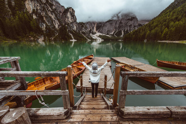 Beautiful woman visiting an alpine lake at Braies, Italy - Tourist with hiking outfit having fun on vacation during autumn foliage - Concepts about travel, lifestyle and wanderlust