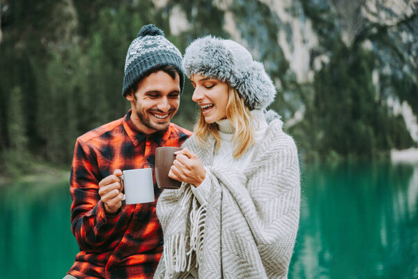 Beautiful couple of young adults visiting an alpine lake at Braies, Italy - Tourists with hiking outfit having fun on vacation during autumn foliage - Concepts about travel, lifestyle and wanderlust