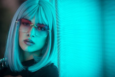 Öncü bir panele poz veren güzel bir genç kadının görüntüsü. Alternatif görünümlü ve gri peruklu genç şehir portreleri yapıyor.