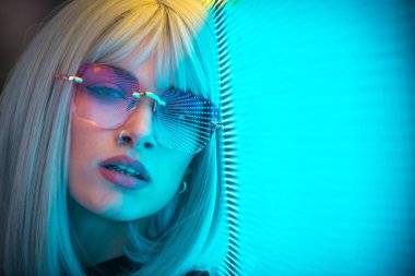 Öncü bir panele poz veren güzel bir genç kadının görüntüsü. Alternatif görünümlü ve gri peruklu genç şehir portreleri yapıyor.