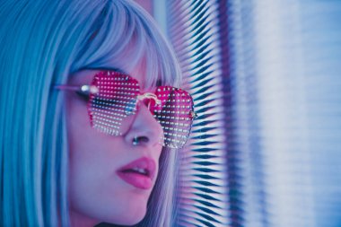 Öncü bir panele poz veren güzel bir genç kadının görüntüsü. Alternatif görünümlü ve gri peruklu genç şehir portreleri yapıyor.