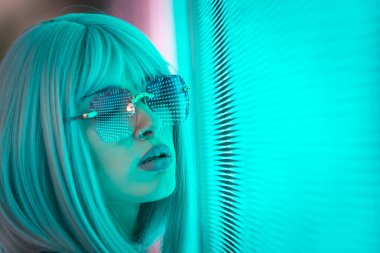 Öncü bir panele poz veren güzel bir genç kadının görüntüsü. Alternatif görünümlü ve gri peruklu genç şehir portreleri yapıyor.