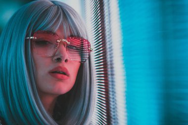 Öncü bir panele poz veren güzel bir genç kadının görüntüsü. Alternatif görünümlü ve gri peruklu genç şehir portreleri yapıyor.