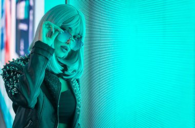 Öncü bir panele poz veren güzel bir genç kadının görüntüsü. Alternatif görünümlü ve gri peruklu genç şehir portreleri yapıyor.