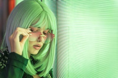 Öncü bir panele poz veren güzel bir genç kadının görüntüsü. Alternatif görünümlü ve gri peruklu genç şehir portreleri yapıyor.