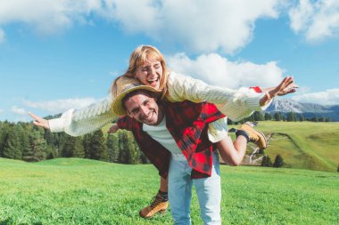 İtalyan Dolomite Dağları 'nda tatilde olan mutlu çift. Genç adam ve kadın yeşil çayırda birlikte oynuyorlar.