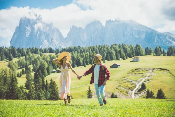 Happy couple on vacation on the italian dolomites mountains. Young man and woman making activities on a beautiful green meadow