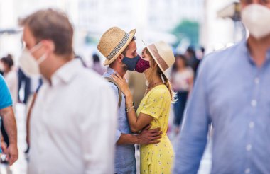 Koruyucu maskeler takan ve öpüşen güzel bir çift, covid-19 salgını sırasında, yaşam tarzı, salgın çağı ve sosyal uzaklık kavramları hakkında