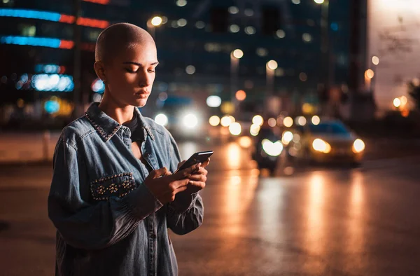 Hezká Dívka Stylovým Oblečením Drží Smartphone Venku Večerních Hodinách Osvětlené — Stock fotografie