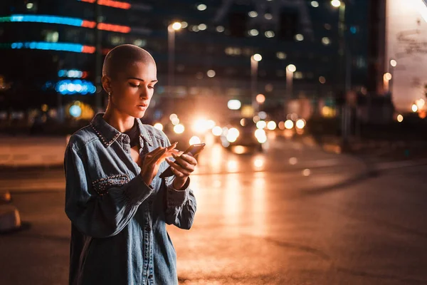 Hezká Dívka Stylovým Oblečením Drží Smartphone Venku Večerních Hodinách Osvětlené — Stock fotografie