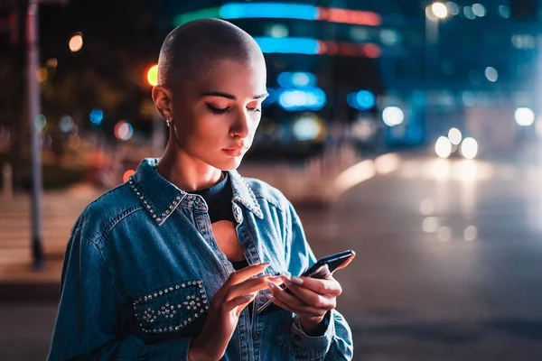 Hezká Dívka Stylovým Oblečením Drží Smartphone Venku Večerních Hodinách Osvětlené — Stock fotografie