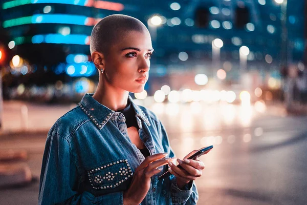 Hezká Dívka Stylovým Oblečením Drží Smartphone Venku Večerních Hodinách Osvětlené — Stock fotografie