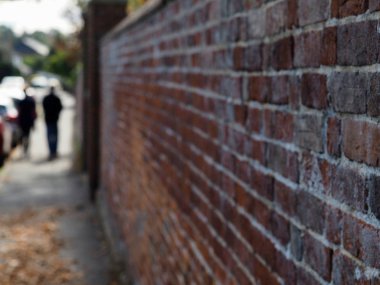 Eski tuğla duvar yüzeyi ve dokusu odak dışı yürüyen figürlerle yakınlaşıyor