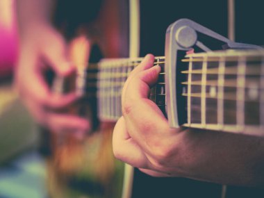 Akustik gitar çalınıyor. Boynu yakın, parmakları müzisyen.