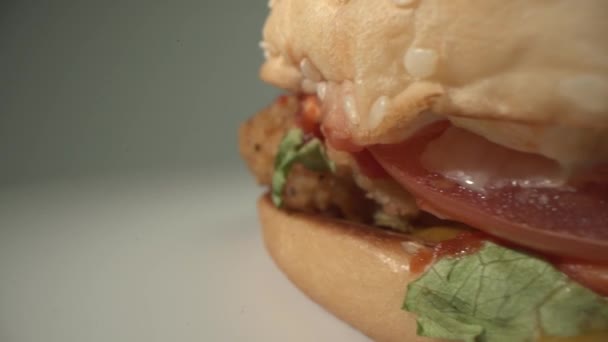 Chutný čerstvý cheeseburger se otáčí na bílém povrchu s pěkným gradientem pozadí. Makro jídlo záběr ze sondy Laowa — Stock video