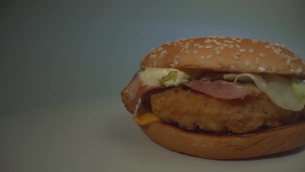 흰 탁자 위의 햄버거요. 슬로우 파노라마 클로즈업. 음식. 다채 로운 배경 — 비디오