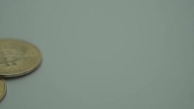 Beyaz yüzeyde üç altın Bitcoin. Yavaş panorama. Makro çekim