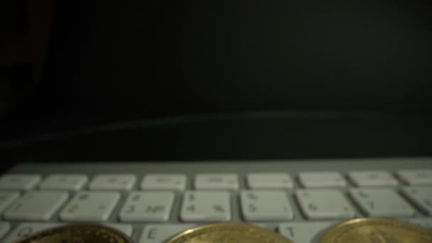 Guld bitcoin på tangentbordet. Kameran rör sig ner från svart bakgrund till kryptomynt. Valuta. Super makro närbild från Laowa 24 mm sond lins — Stockvideo