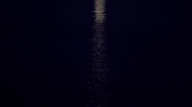 Kamera ay yolu boyunca yavaş yavaş Ay 'dan gece yarısı sakin mavi denize iniyor.