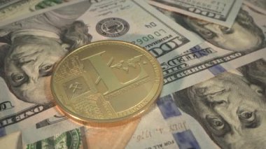 Altın Kripto sikkesi Litecoin yalanı ve 100 dolarlık banknotlar. Yüzeyde dönüyor. Yakın plan çekim. Geleceğin dijital parası..