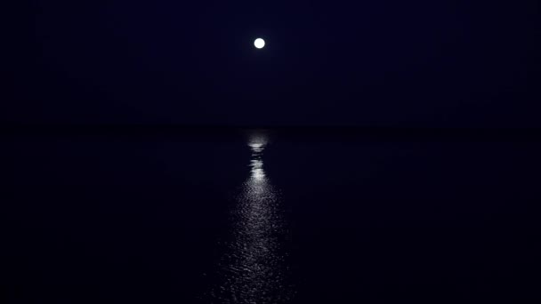 The full moon hangs very low above the horizon in a very calm sea two hours before dawn. The lunar path extends along the entire sea to the coast — Stock Video