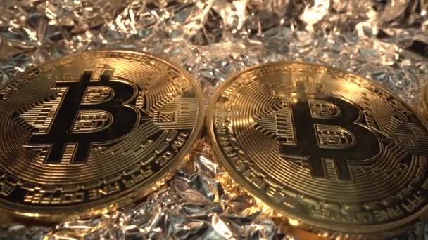 Drie gouden munten BITCOIN op de achtergrond. Camera panorama van links naar rechts. Macro shot van Laowa 24 mm sonde lens. De helft. Ruilen. Geld van de toekomst. Digitale valuta — Stockvideo