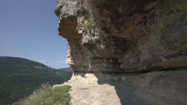 Z obrovské skály do kaňonu s mnoha zelenými stromy a vesnicí. Fantastický výhled. Slunečný den. Cestovní video. Divoká příroda. Výstřel z okraje. — Stock video