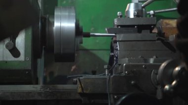 Kafa bandı ve koruyucu tulum giyen profesyonel bir vatman küçük tanker atölyesinde dikkatlice metal torna yapıyor.