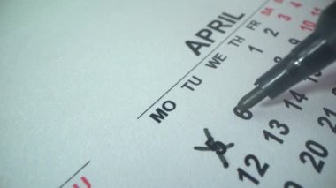 Takvim 2021. Nisan. Kadınlar ayın ikinci haftasında tarihleri çizerler. Cumartesiyi de hafta sonu olarak düşün. Siyah kalem. Makro çekim.