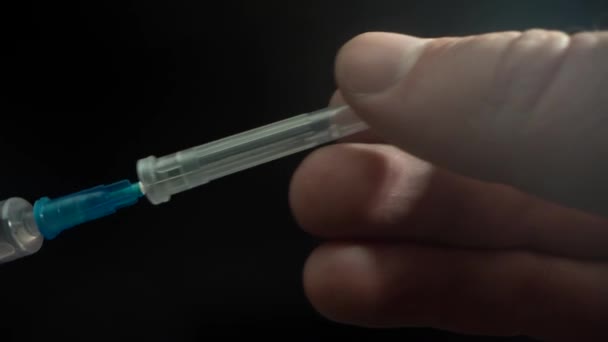 Lékař připraví injekční stříkačku s jehlou pro aplikaci vakcíny pacientovi. Sundá z jehly uzávěr. Makro medicína. Laowa. — Stock video
