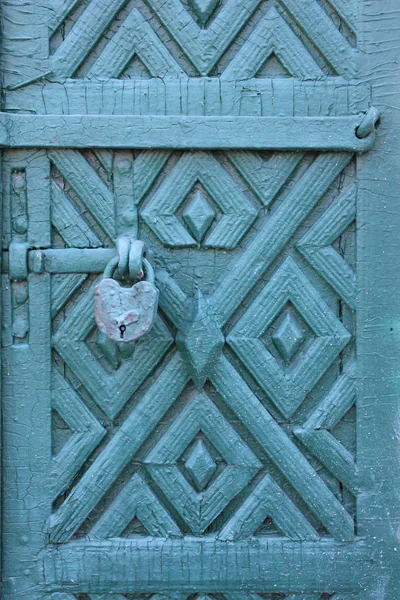 Old blue painted door with bar and lock and ornament