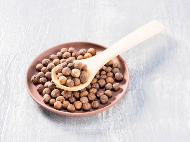 Allspice (Jamaika biberi) kil plaka ve ahşap kaşık diyagonasında