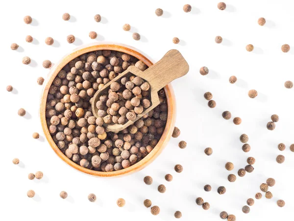 Allspice (pimienta de Jamaica) en taza de madera y cucharada en respaldo blanco — Foto de Stock