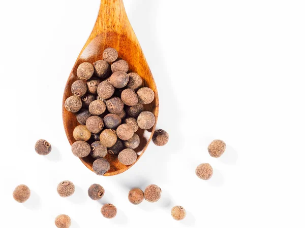 Allspice (pimenta da Jamaica) na colher de madeira verticalmente no whit — Fotografia de Stock