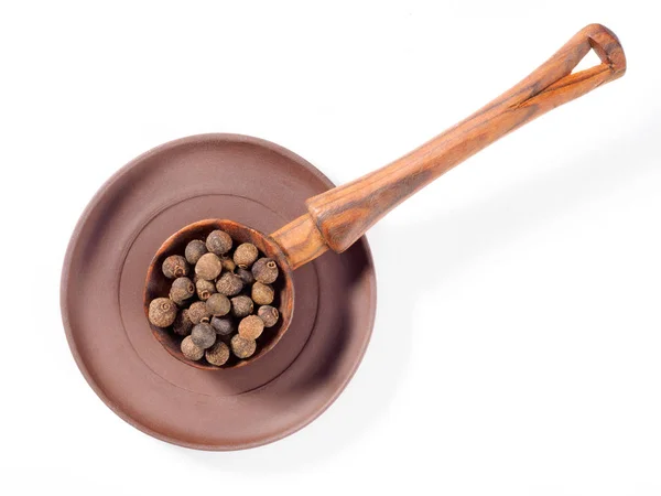 Pimento (pepe giamaicano) in piatto di argilla e cucchiaio di legno diagona — Foto Stock