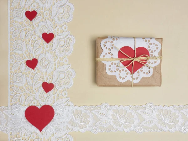 White laces on a beige background with red hearts and present — Stock Photo, Image