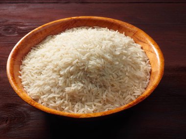 Kahverengi ahşap arka planda bambu kasesinde beyaz basmati pilavı.