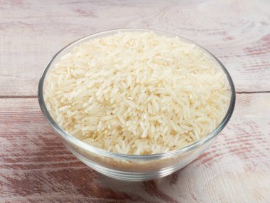 Beyaz kahverengi bir tahta sırtında cam bir kasede çiğ Basmati pilavı.