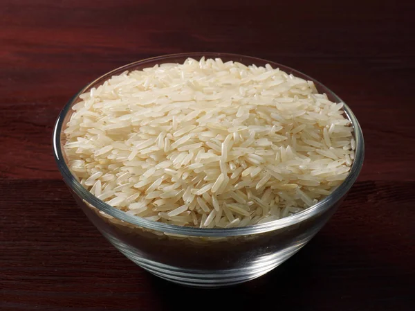 Arroz basmati blanco en un recipiente de vidrio sobre un fondo de madera marrón — Foto de Stock