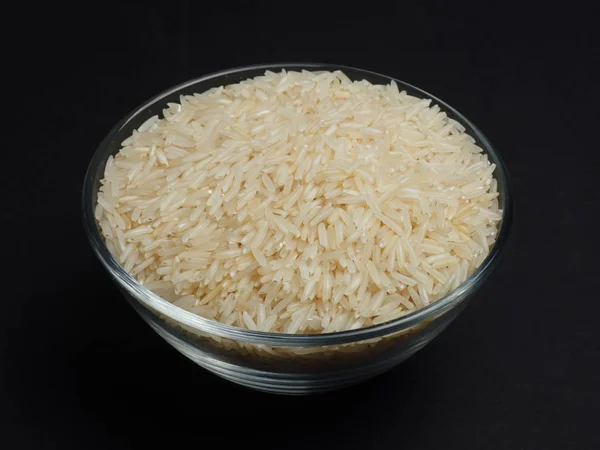 Arroz basmati blanco en un recipiente de vidrio sobre un fondo negro — Foto de Stock