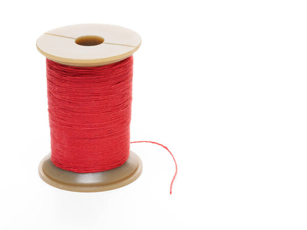 Красная катушка резьбы в вертикальном положении на белом фоне
