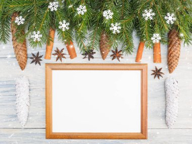 Fir tree branch with cones, cinnamon, anise, frame, snowflake on