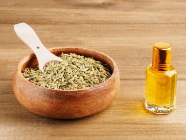 Fennel seeds (Foeniculum vulgare) in brown cup with scoop and ar