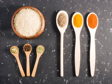 Siyah beton arka planda pirinç ve baharatlar. Hint mutfağı.