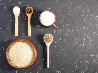 Siyah beton arka planda pirinç ve baharatlar. Hint mutfağı.